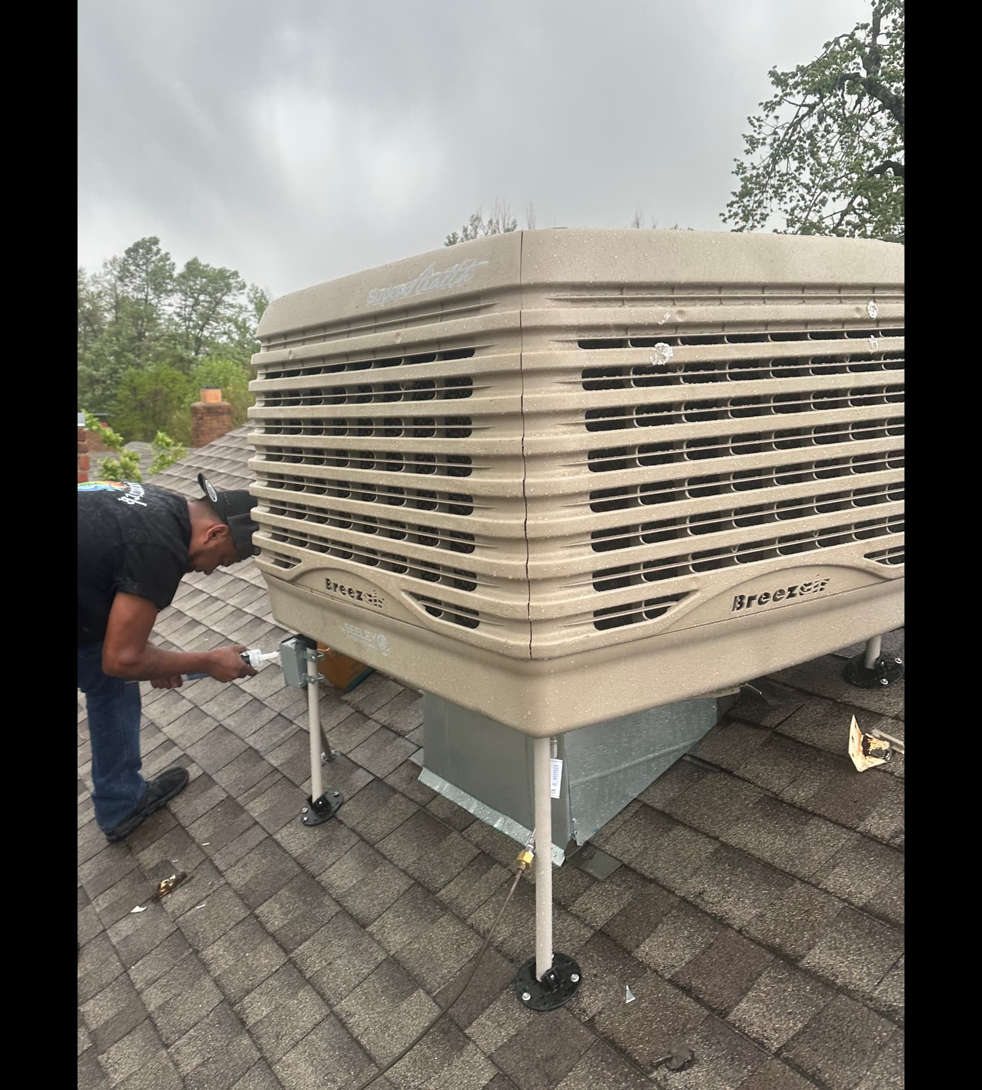 HVAC technician servicing Breezair evaporative cooler on Denver rooftop